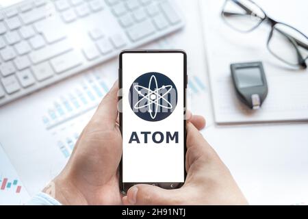 Logo of Atom coin in tablet. Cryptocurrency Cosmos token. Trading blockchain platform to buy,sell on decentralized exchange DEX,DEFI. Digital money.Bu Stock Photo