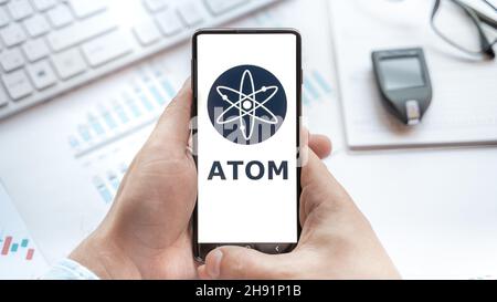 Logo of Atom coin in tablet. Cryptocurrency Cosmos token. Trading blockchain platform to buy,sell on decentralized exchange DEX,DEFI. Digital money.Bu Stock Photo
