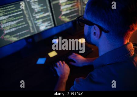 Close up cropped rear back portrait of young developer texting typing improving database late house dark room Stock Photo