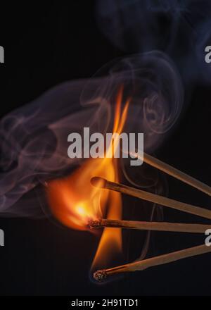artistic shot of Matchsticks igniting and burning against a dark background. Stock Photo