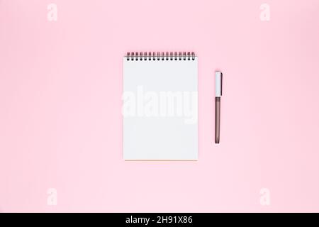 White blank open spiral notebook and pen isolated on pastel pink background. Flat lay, copy space. Creative work, business, finance or education concept Stock Photo