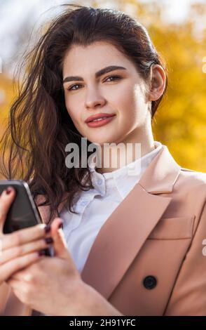 Young beautiful business woman making a cell phone call in autumn park Stock Photo