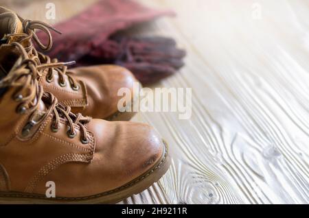 Yellow leather used work boots and protective gloves on wooden background closeup. Place for text Stock Photo