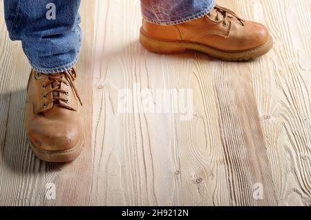 Carpenter feet in work boots standing on wooden floor. Place for text Stock Photo