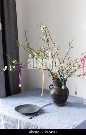 Blooming cherry branches decorated with colorful ribbons with easter eggs, Happy Easter, table setting Stock Photo