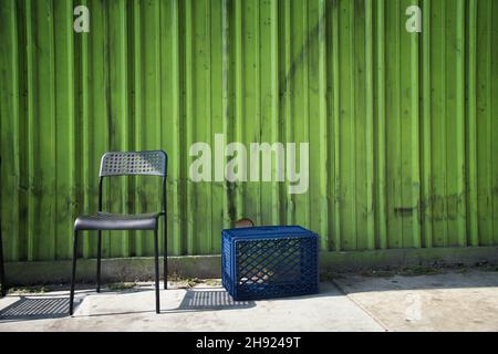 A metal chair and a blue plastic milk crate sit on the sidewalk in Los Angeles, CA. Stock Photo