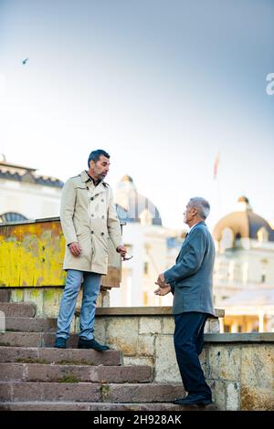 Two amazing senior businessmen are talking on the stairs Stock Photo