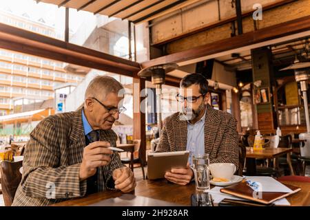 Two senior businessmen are having a discussion about the documents on the tablet Stock Photo