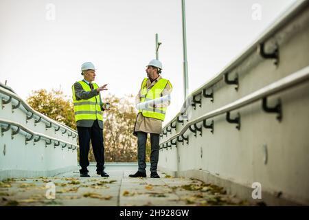 Two senior construction managers are standing and having a conversation about the plans Stock Photo