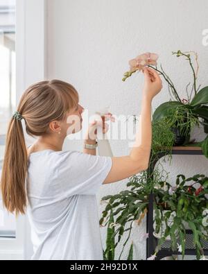 Portrait of young female taking care of houseplants and flowers on balcony Stock Photo