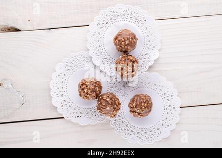 Several sweet chocolates with nuts with paper white napkins on a wooden table, close-up, top view. Stock Photo