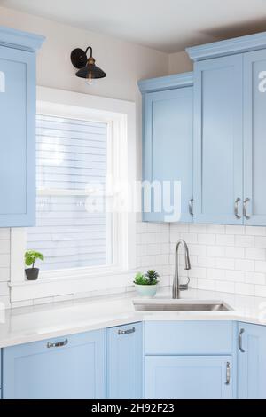 https://l450v.alamy.com/450v/2h92f23/detail-of-a-kitchen-with-light-blue-cabinets-white-granite-countertop-subway-tile-backsplash-and-a-light-hanging-above-a-window-2h92f23.jpg