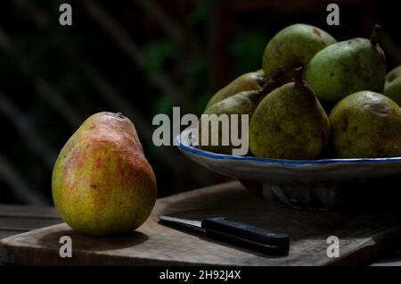 Single pear fruit and a cup with pears on the wooden board Stock Photo