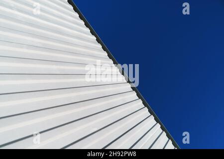 Textured white metal structures diagonally against a blue sky. Abstraction in buildings Stock Photo