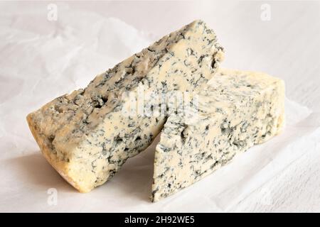 Two blue cheese wedges on white wax paper. Stock Photo