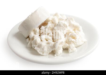 Round of goat cheese and crumbled goat cheese on white ceramic plate isolated on white. Stock Photo