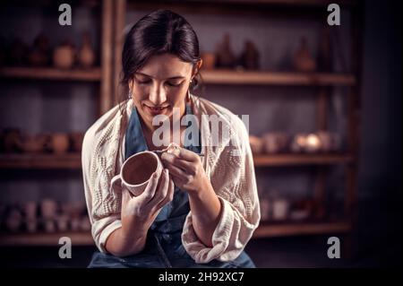 Beautiful female master making ceramic pot on the pottery wheel . Craft production. Stock Photo