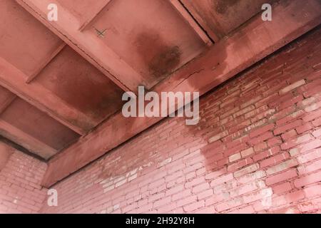 Old brick facade wall with leaking roof and wet water stain on the surface. Stock Photo