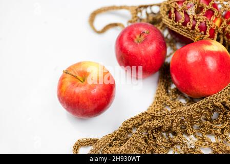 fruits apples red in a knitted string bag on an isolated white background Stock Photo