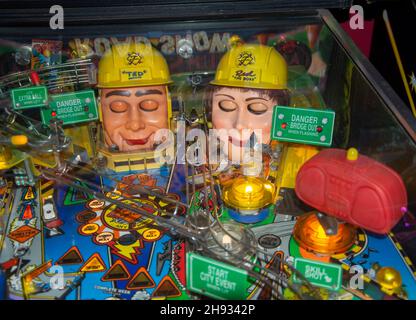 A pinball game machine in an arcade. The game include two heads with their eyes closed Stock Photo
