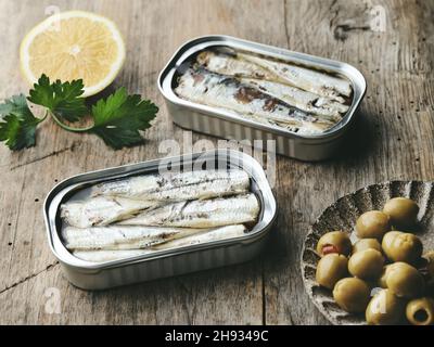 open sardines cans and olives on rustic wooden table Stock Photo