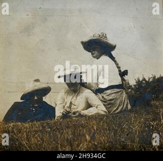 Vintage photograph of Father and daughters laid down on grass, Edwardian summer day out, English, anonymous, 1910s