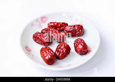 Dried Chinese red jujube in a plate isolated on white background. Stock Photo