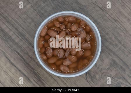 Overhead view of generous portion of pinto beans in a container to eat as a side order with the meal. Stock Photo