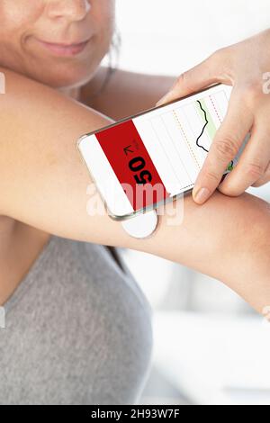 Diabetic woman monitoring and checking glucose level with a remote sensor and a new technology with an app in smartphone Stock Photo