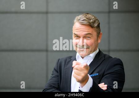Upper body portrait of confident middle aged businessman smiling and pointing with finger Stock Photo