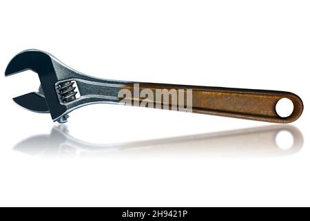 Closeup of a stainless steel adjustable wrench with rusty handle, isolated on white background with reflections. Stock Photo