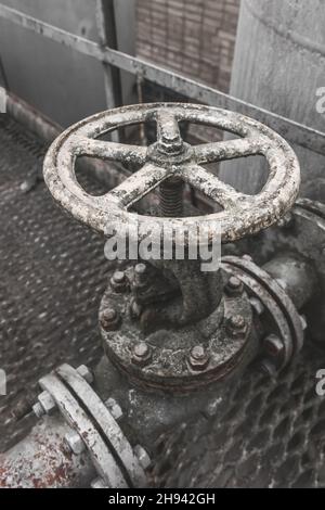 Old valve for opening or shutting down pipeline for fuel oil chemical tanks in an abandoned industrial plant. Stock Photo