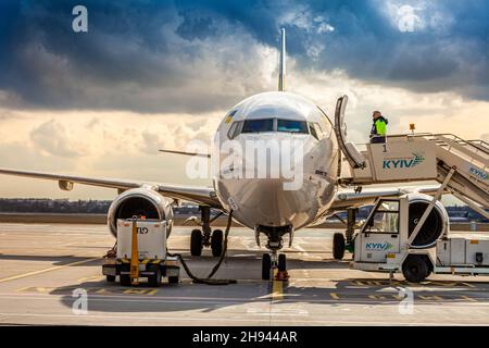 Bees Airline yellow plane on the apron. Boeing 737-800 UR-UBA Passenger aircraft. After rain and washing. Copy space runway. Ukraine, Kyiv - March 19, 2021. Stock Photo