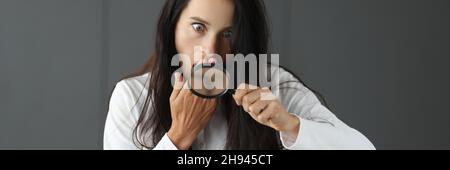 Surprised woman looking through magnifying glass and covering mouth with hand Stock Photo
