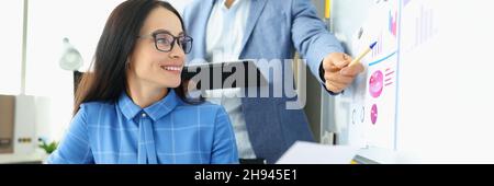 Business man explaining information to woman on blackboard with graphs and diagrams Stock Photo