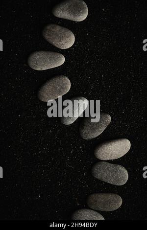 small sea pebbles are laid out on a black background Stock Photo