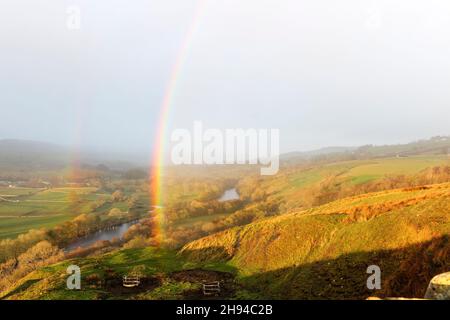 Middleton-in-Teesdale, County Durham, UK.  4th December 2021. UK Weather.  A spectacular rainbow appears over the Tees valley as heavy rain, sleet and snow showers sweep into Upper Teesdale where teams are still working to bring electricity to homes cut off during storm Arwen 8 days ago.  Credit: David Forster/Alamy Live News Stock Photo
