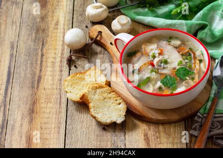 Traditional rustic thick german pea soup with smoked bacon, mushrooms and cereals on wooden table. Hot dinner or lunch.  Copy space. Stock Photo