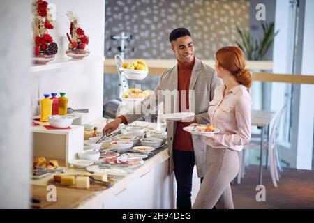 Two young work colleagues having breakfast together in the office Stock Photo