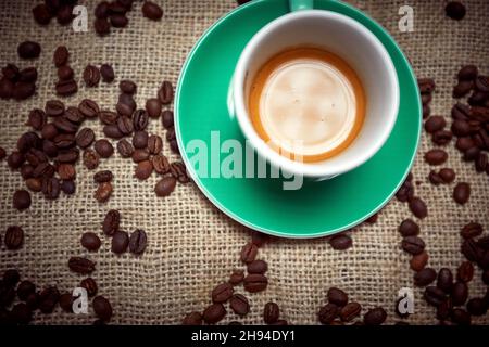 Bird-eye view of aromatic and fragrant espresso coffee in a cup standing on a bag with coffee beans. Coffee, beverage Stock Photo