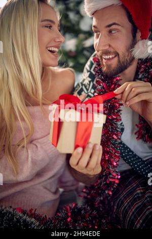 Happy woman surprising her men girl with a present at Christmas.. Stock Photo
