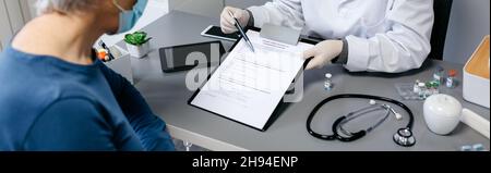 Doctor explaining to her patient consent form to coronavirus vaccine Stock Photo