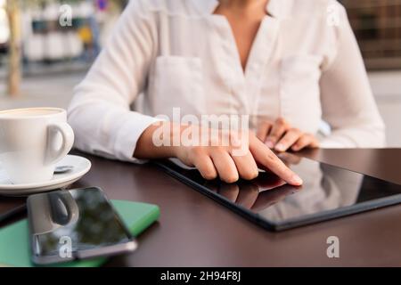 hand of a woman using a digital tablet on the terrace of a coffee shop, concept of digital entrepreneur and urban lifestyle Stock Photo