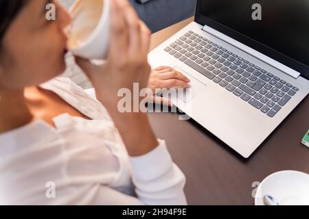 unrecognizable businesswoman working with her computer while drinking coffee on a terrace, concept of digital entrepreneur and urban lifestyle Stock Photo