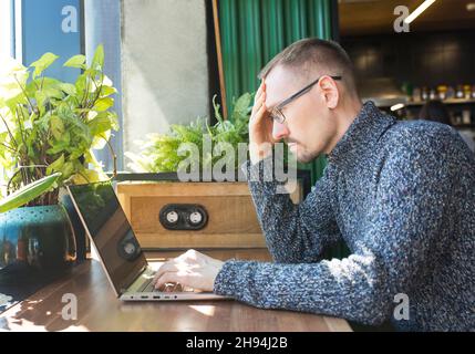 Tired businessman is trying to solve problem with work. A Man sits with serious face in front of computer. Stock Photo