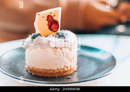 Close up delicious cheesecake with lavender, blueberry, cream and strawberry white chocolate. Served on a black plate at a patisserie. Stock Photo