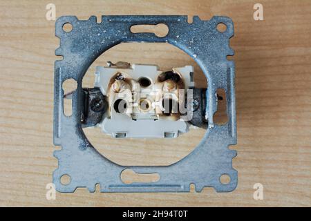 Broken power overload switch electric outlet. Electric short circuit causing fire on plug socket. Stock Photo
