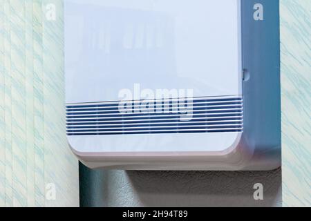 ventilation openings of a device in a white plastic case mounted on a wall in an office or apartment, selective focus Stock Photo