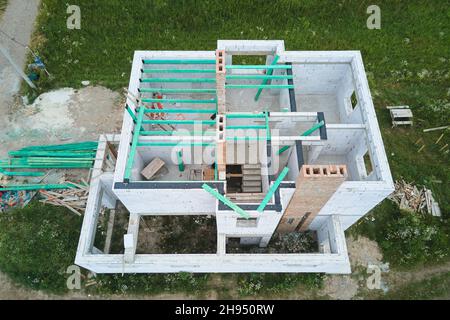 Aerial view of unfinished frame of private house with aerated lightweight concrete walls and wooden roof beams under construction. Stock Photo