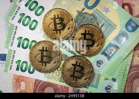 Bitcoin physical coin laying on top of 100 Euro bills. Stock Photo